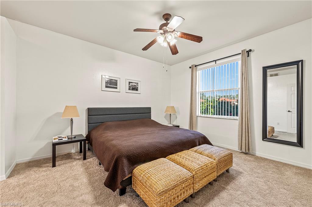 280 Robin Hood Circle, Unit 101 Naples, FL 34104 - Photo 12 of 19 a bedroom with a bed and a chandelier