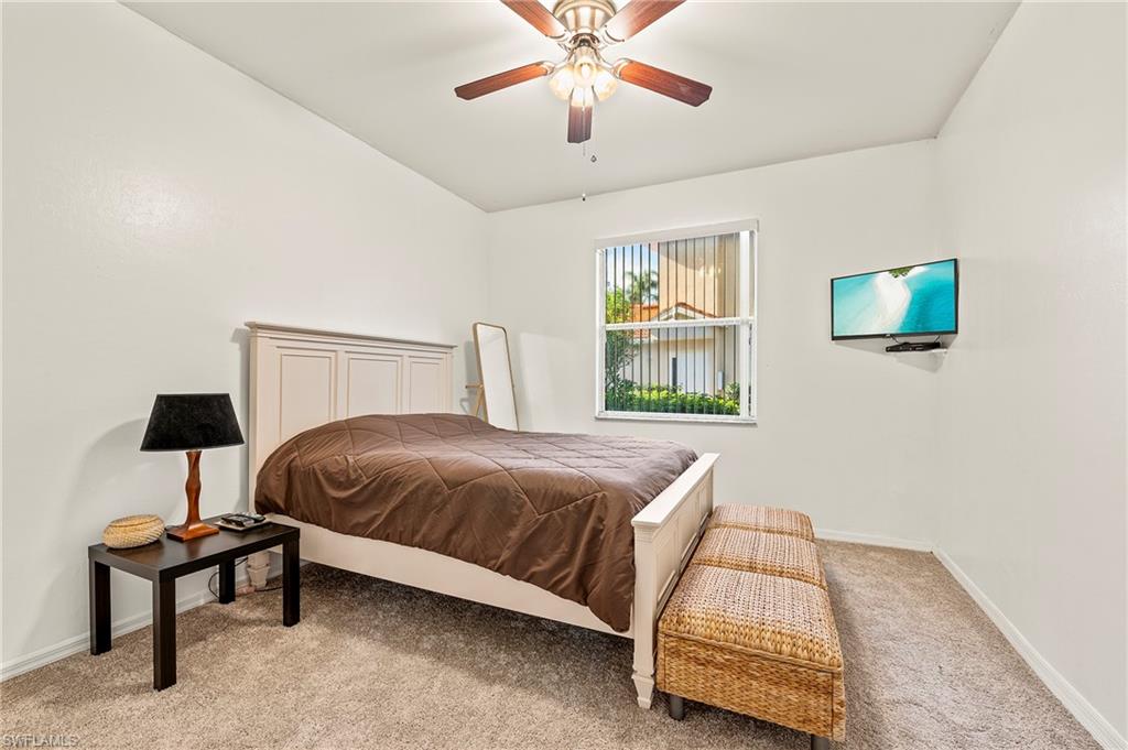 280 Robin Hood Circle, Unit 101 Naples, FL 34104 - Photo 14 of 19 a bedroom with a bed and a chandelier