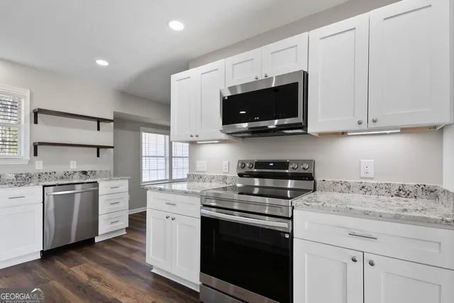 a kitchen with stainless steel appliances granite countertop a stove a sink and a microwave