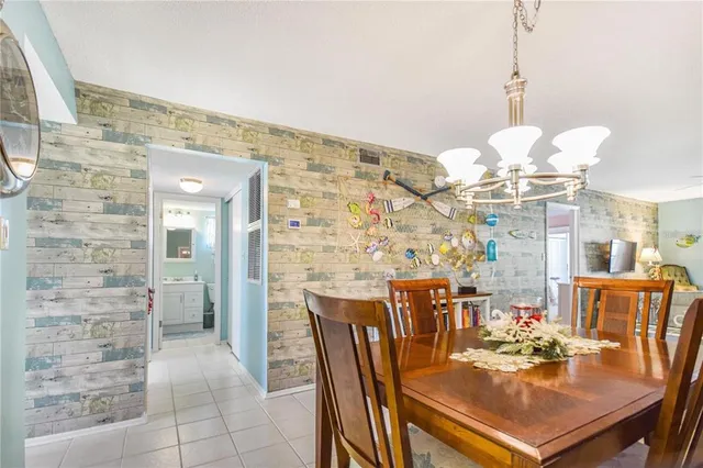 a dining room with furniture a chandelier and kitchen view
