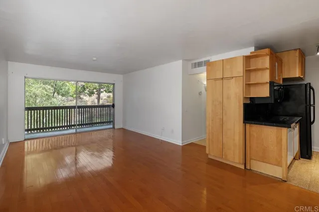 a view of a livingroom with wooden floor and a kitchen
