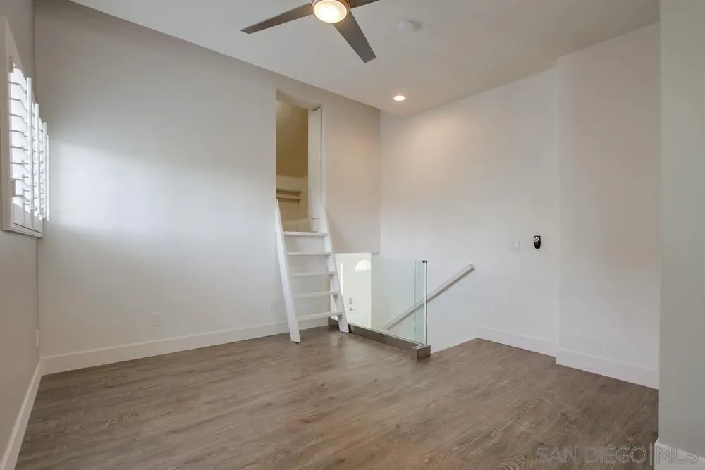 1764 Whitehall Road Encinitas, CA 92024 - Photo 16 of 25 an empty room with wooden floor ceiling fan and windows