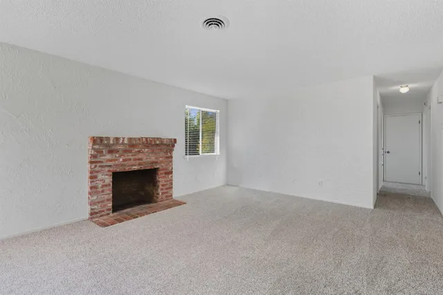 a view of an empty room with a fireplace and a window