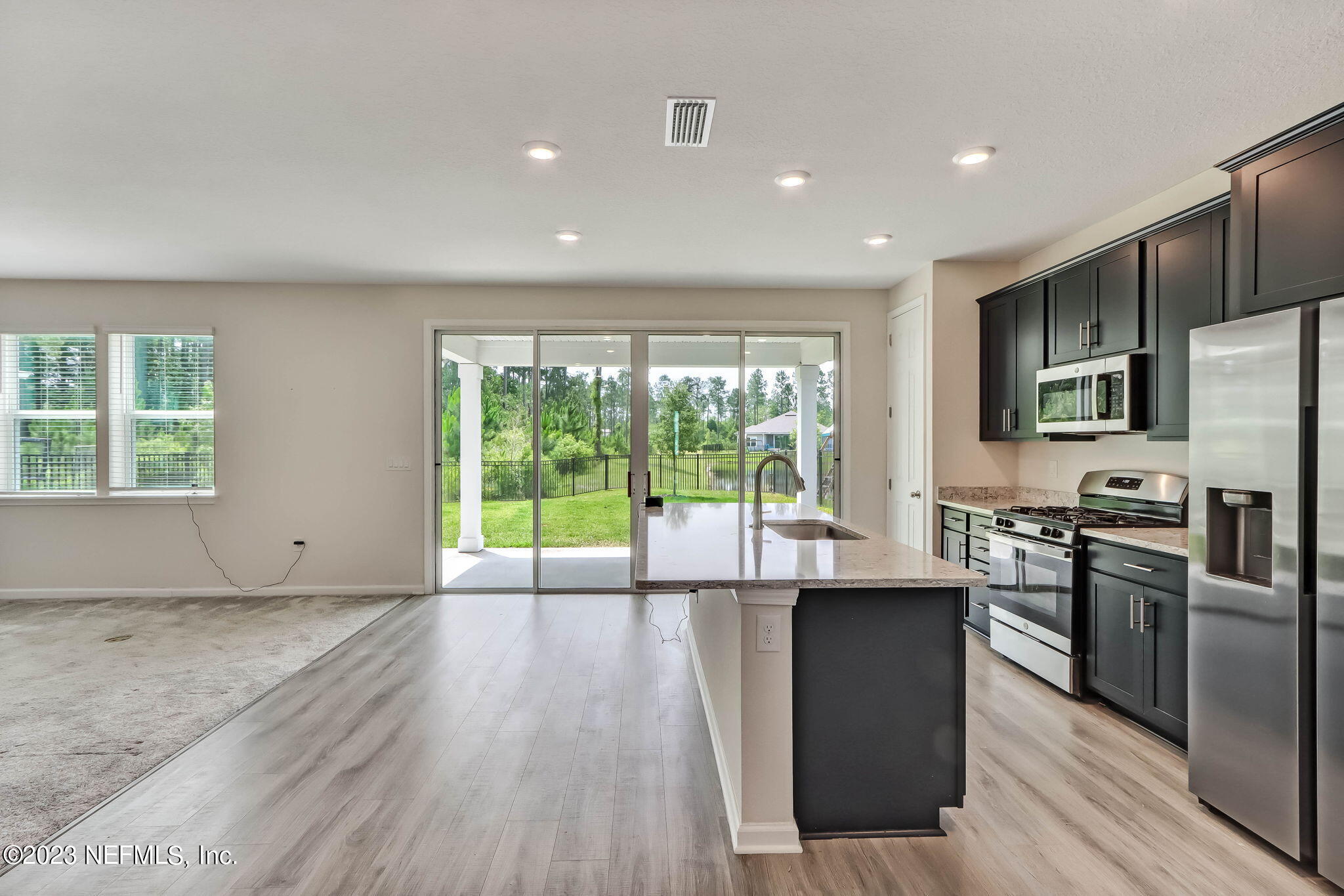 75944 Saffron Lane Yulee, FL 32097 - Photo 7 of 79 a kitchen with stainless steel appliances granite countertop a stove a sink a refrigerator with wooden floors and wooden cabinets