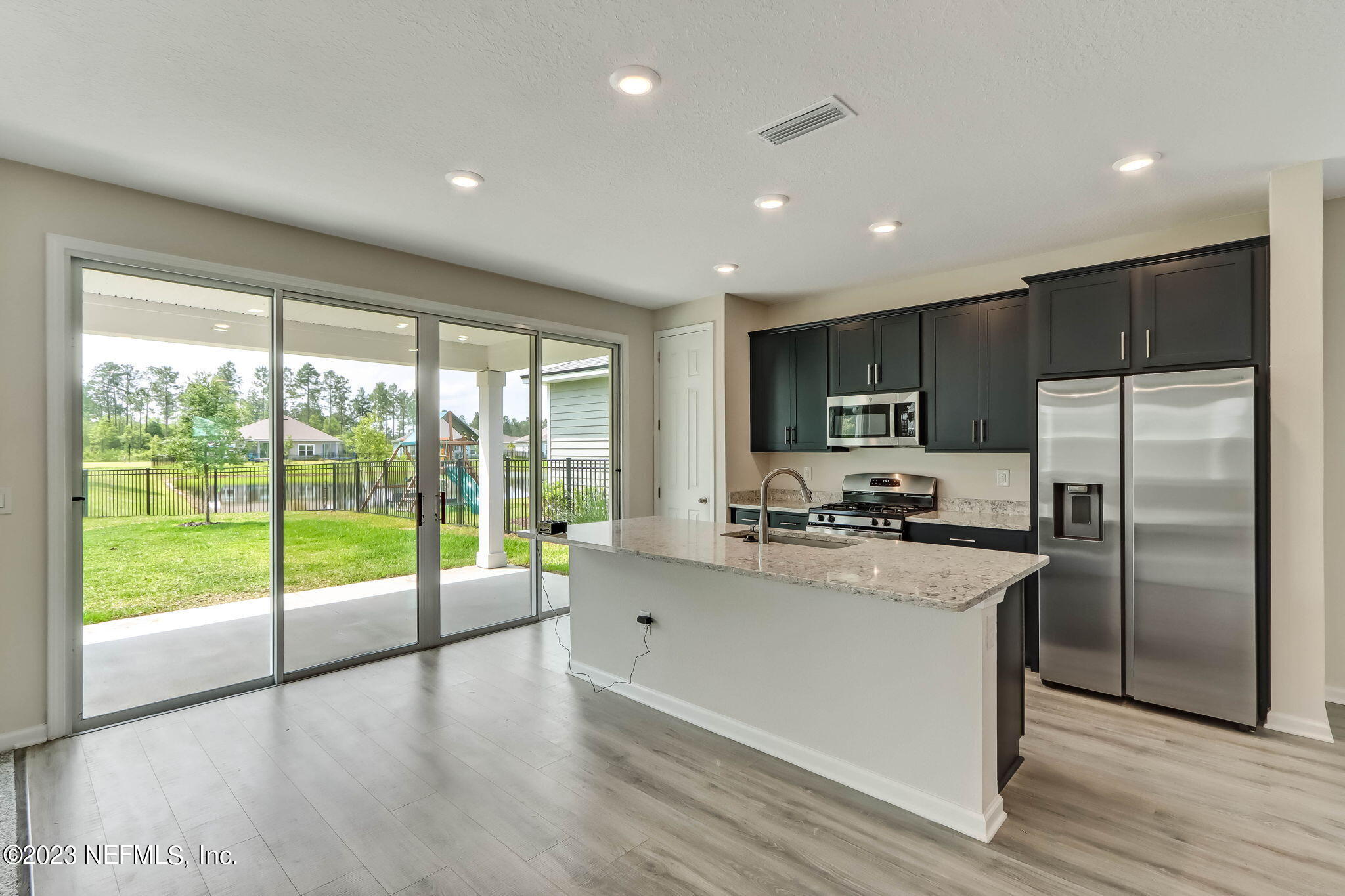 75944 Saffron Lane Yulee, FL 32097 - Photo 9 of 79 a kitchen with refrigerator a stove a sink and a center island with wooden floor