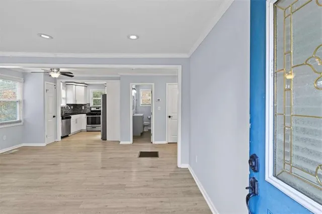 a view of a hallway with wooden floor and a bathroom