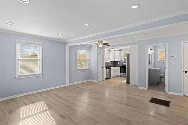 a view of an empty room with wooden floor and a window