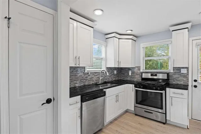 a kitchen with stainless steel appliances a stove and white cabinets