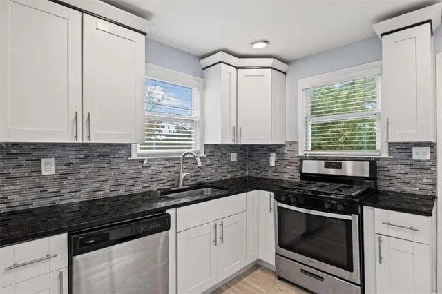 a kitchen with granite countertop cabinets stainless steel appliances a sink and a window