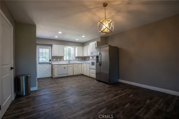 a kitchen with stainless steel appliances granite countertop a refrigerator a sink dishwasher a stove and white countertops with wooden floor