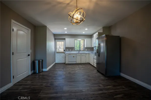 a view of a kitchen with a refrigerator a ceiling fan and wooden floor
