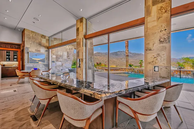 a view of a dining room with furniture a fireplace and large windows