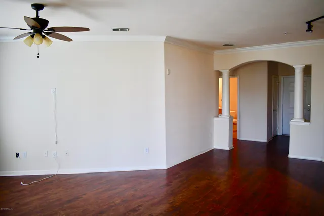 a view of an empty room with window and wooden floor