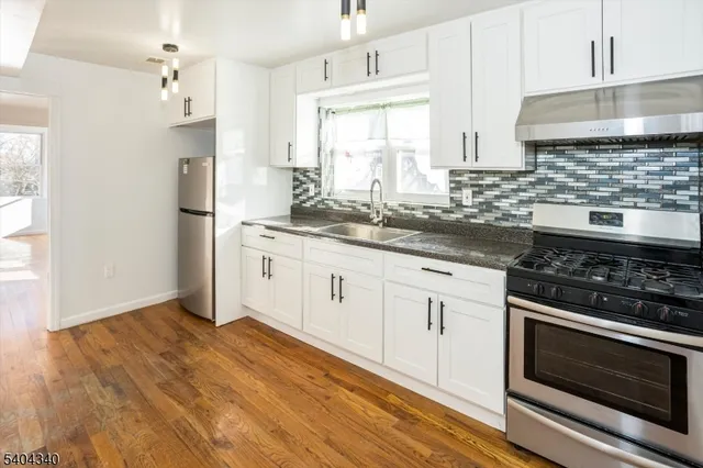 a kitchen with stainless steel appliances white cabinets and a stove a sink