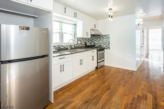 a kitchen with a refrigerator a sink and dishwasher with wooden floor