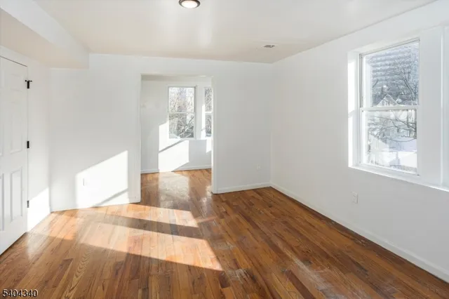a bedroom with wooden floor and window