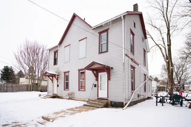 a view of a white house with a large tree