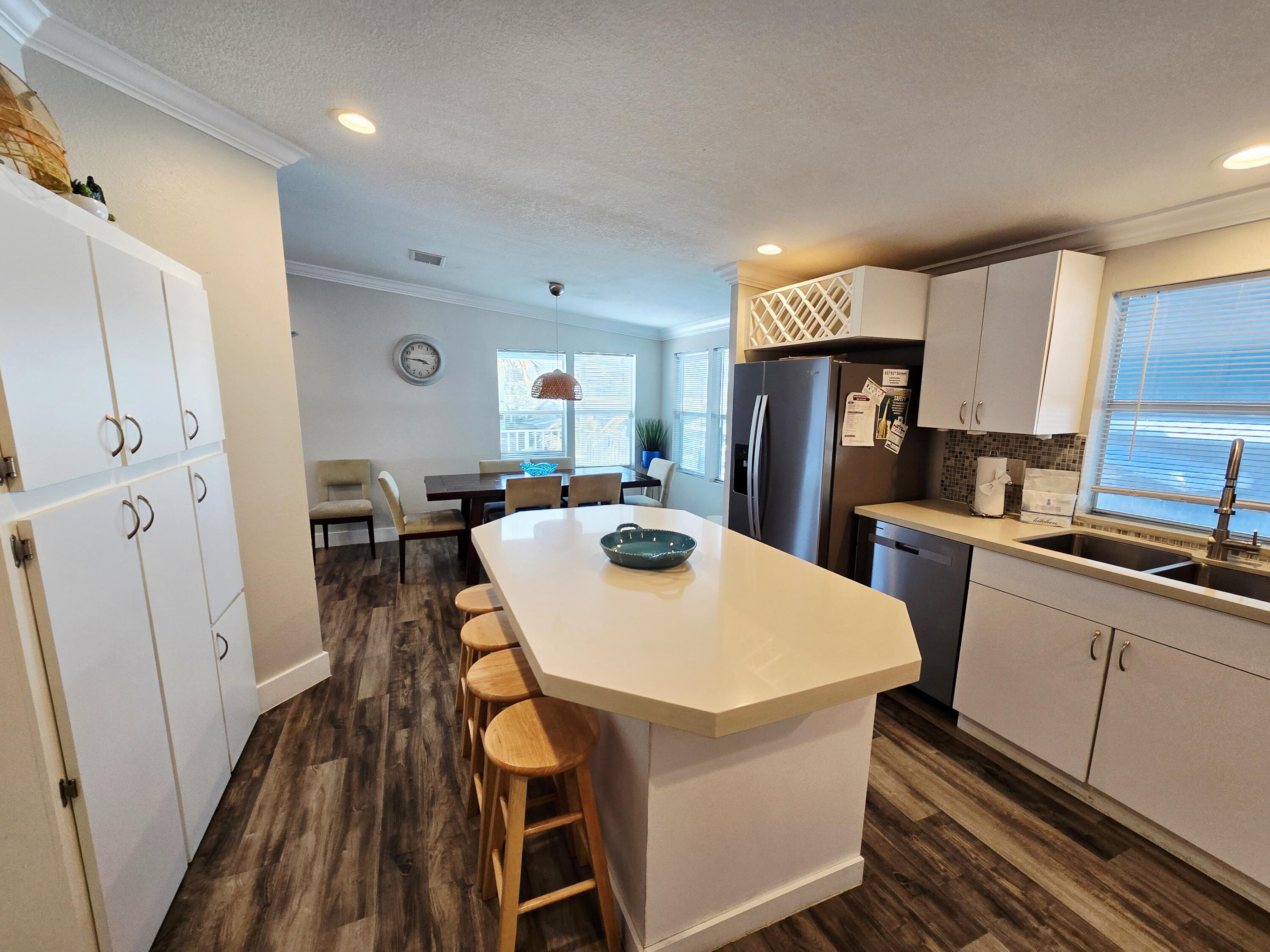 837 91st St Ocean Marathon, FL 33050 - Photo 11 of 27 a kitchen with stainless steel appliances a refrigerator a stove a sink dishwasher and white cabinets with wooden floor