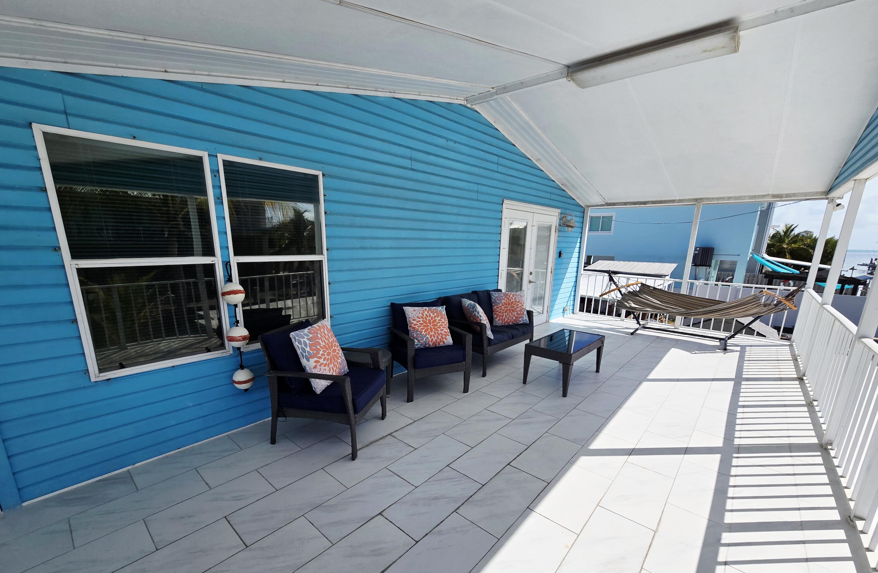 837 91st St Ocean Marathon, FL 33050 - Photo 24 of 27 a view of a patio with dining table and chairs with wooden floor and fence