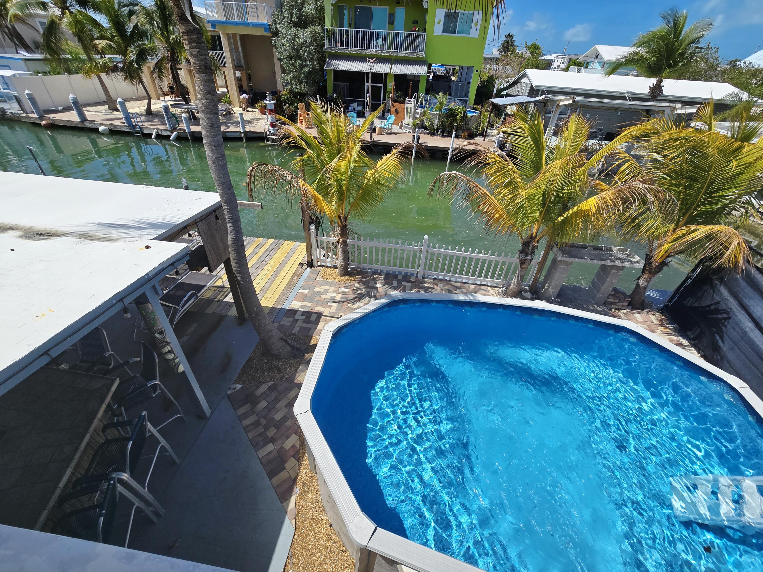 837 91st St Ocean Marathon, FL 33050 - Photo 25 of 27 a view of a swimming pool with outdoor seating and plants