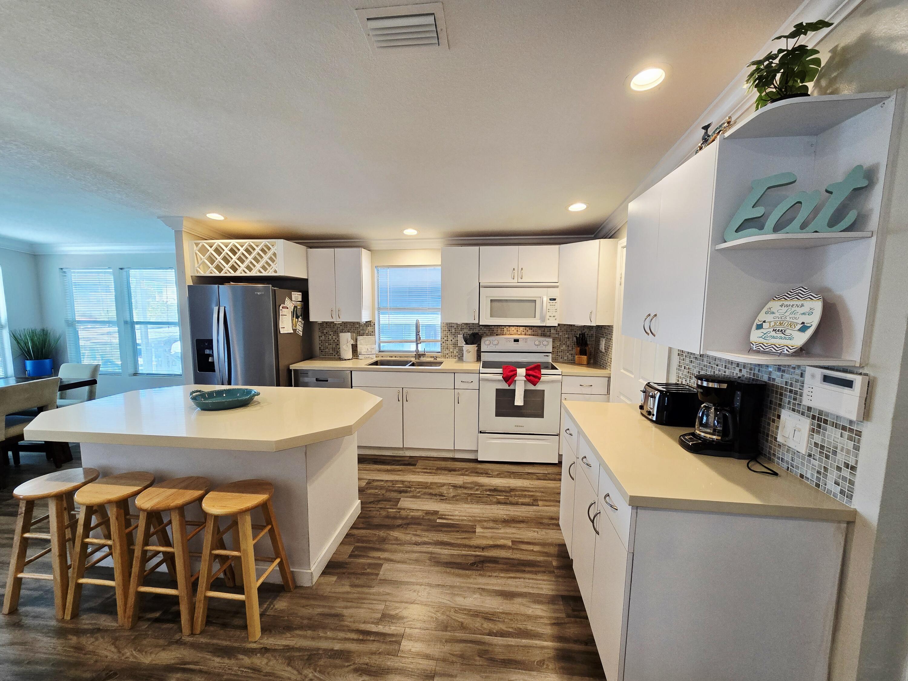 837 91st St Ocean Marathon, FL 33050 - Photo 10 of 27 a kitchen with stainless steel appliances granite countertop a refrigerator a stove and a sink with wooden floor