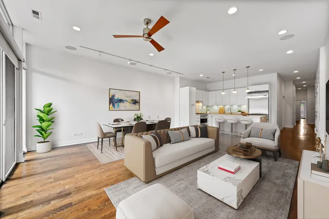 a view of an empty room with wooden floor and fan