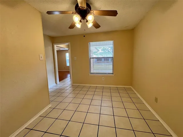 a view of an empty room and chandelier fan