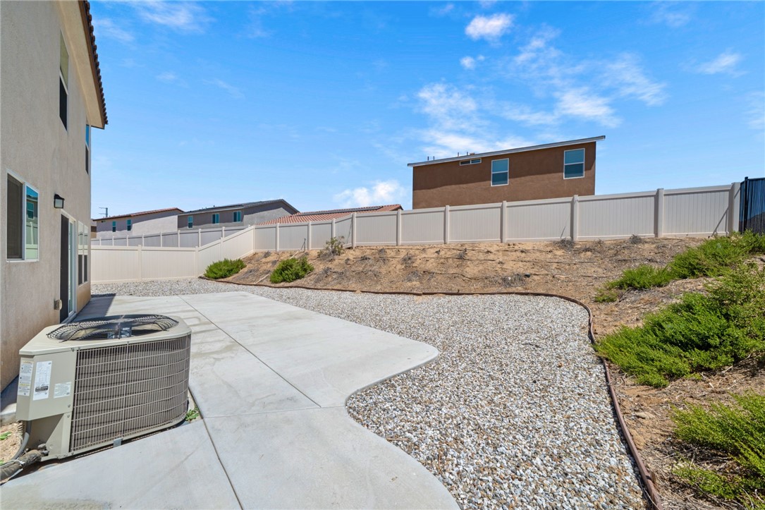 20130 Curaco Court Riverside, CA 92507 - Photo 38 of 43 Backyard with a concrete patio, gravel landscaping, shrubs, and fencing.