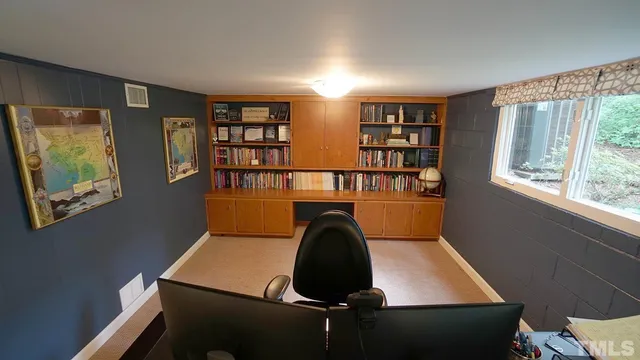 a view of a workspace with furniture and a window