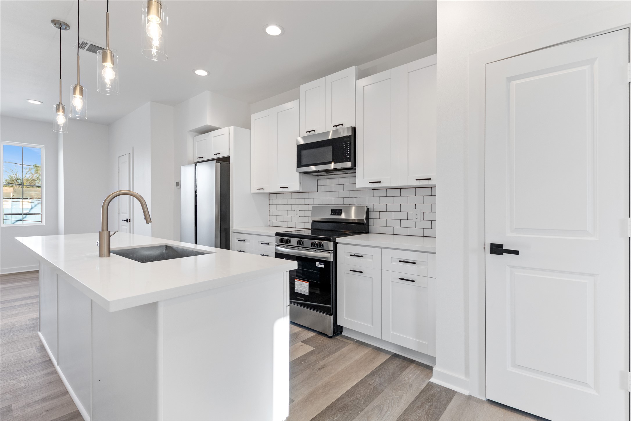 2702 Winbern Street, Unit A Houston, TX 77004 - Photo 11 of 16 a kitchen with stainless steel appliances kitchen island a white stove top oven and refrigerator