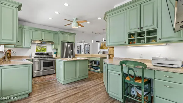 a kitchen with stainless steel appliances a sink a stove a chimney a large window and cabinets