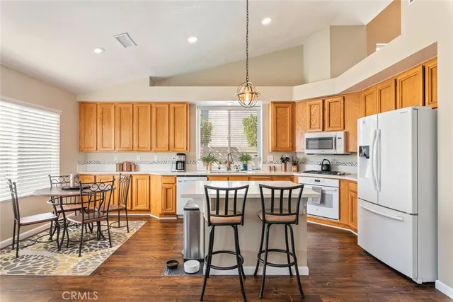 a kitchen with stainless steel appliances a dining table chairs refrigerator and sink
