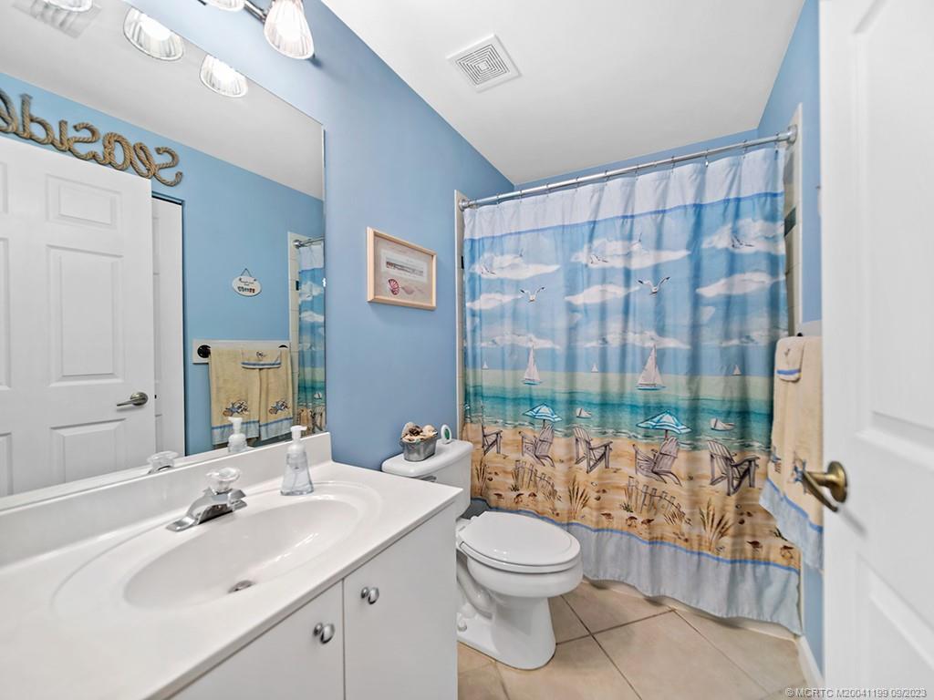 2498 Southeast Springtree Place Stuart, FL 34997 - Photo 13 of 25 a bathroom with a toilet a sink and a large mirror