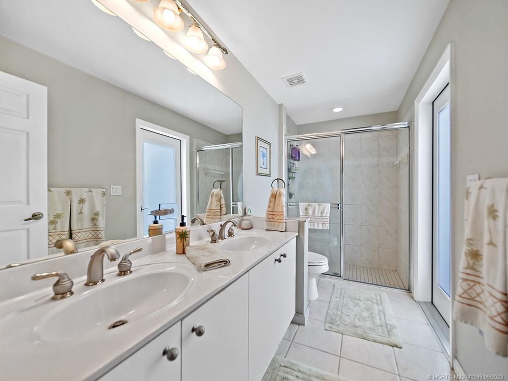 2498 Southeast Springtree Place Stuart, FL 34997 - Photo 17 of 25 a bathroom with double vanity sinks a shower and a mirror
