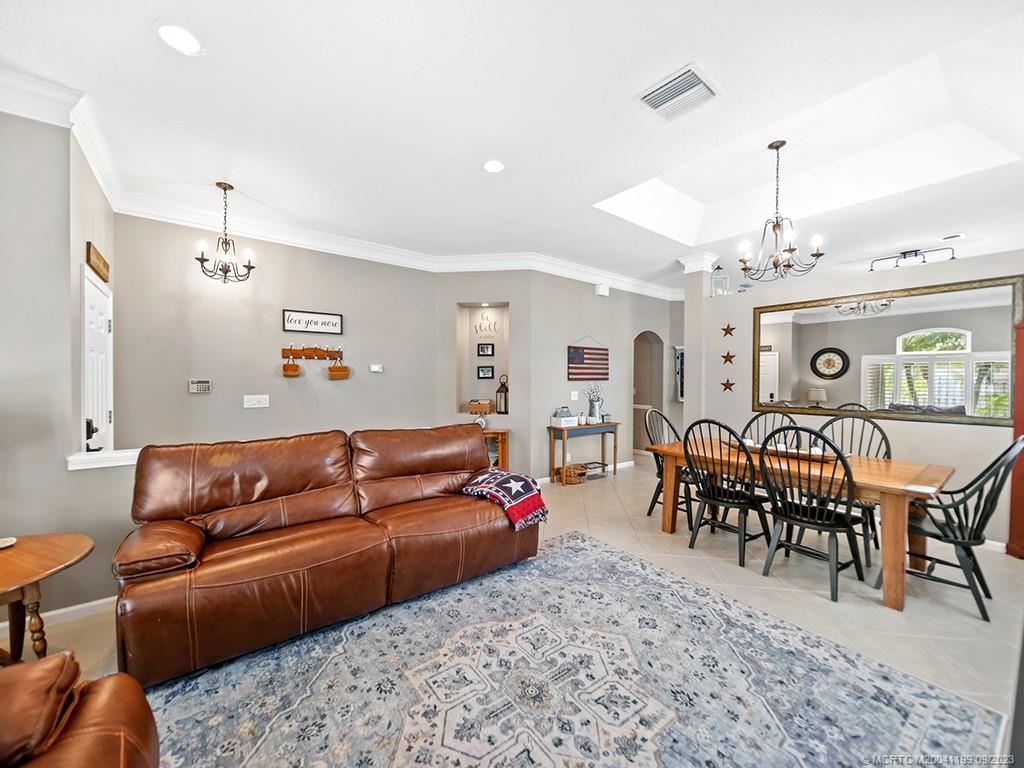 2498 Southeast Springtree Place Stuart, FL 34997 - Photo 5 of 25 a living room with furniture a chandelier and a dining table