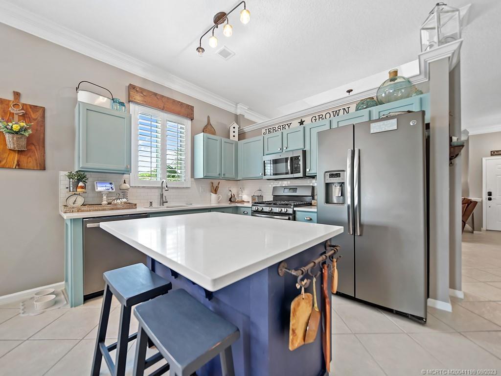 2498 Southeast Springtree Place Stuart, FL 34997 - Photo 7 of 25 a kitchen with stainless steel appliances granite countertop a table chairs refrigerator and microwave