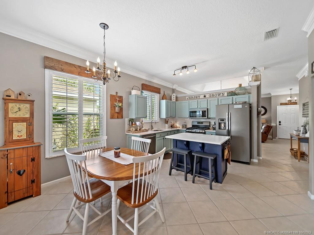 2498 Southeast Springtree Place Stuart, FL 34997 - Photo 10 of 25 a dining room with furniture a chandelier and kitchen view