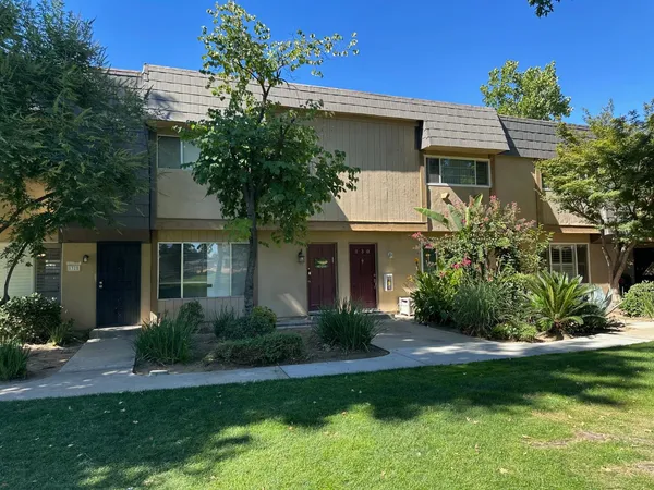 a front view of a house with a yard and potted plants