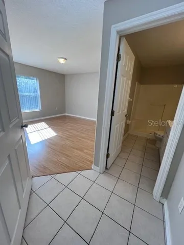 a view of an empty room with wooden floor and a window