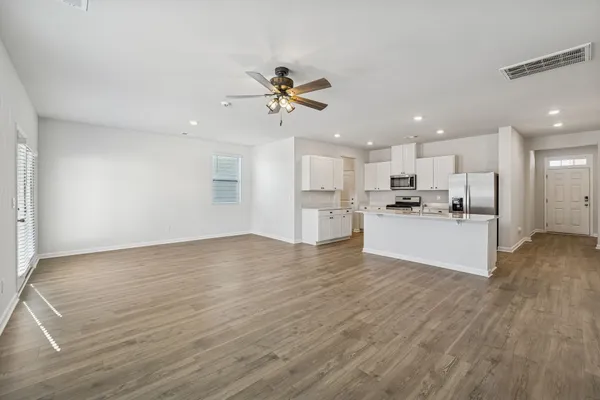 a view of kitchen with granite countertop a stove top oven a refrigerator a sink and white cabinets with wooden floor