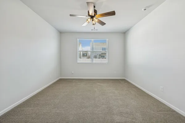 an empty room with a window and a fan