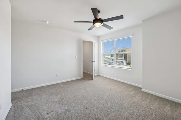 an empty room with a ceiling fan and carpet