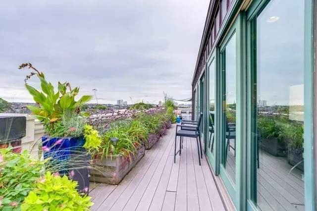 a balcony with wooden floor table and chairs