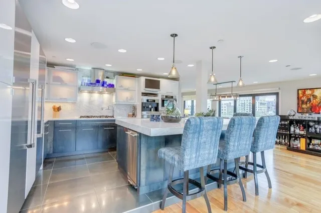 a kitchen with stainless steel appliances kitchen island granite countertop a table chairs sink and cabinets