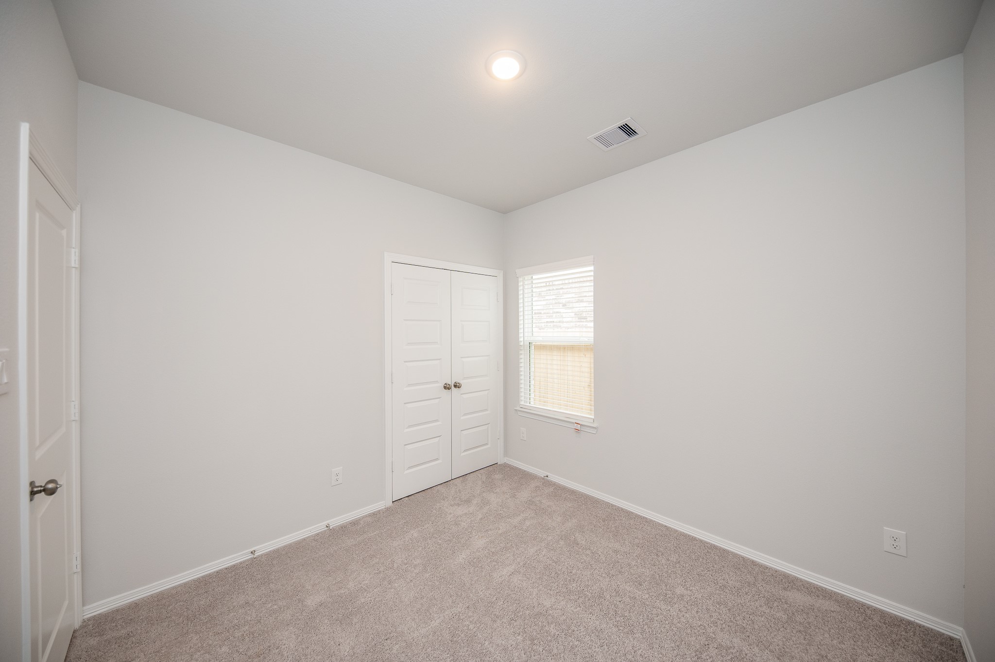 23302 Spring Genesis Lane Katy, TX 77493 - Photo 27 of 32 This room features neutral walls and carpet, providing a clean and versatile space. It includes a double-door closet and a window for natural light, ideal for a bedroom or home office.