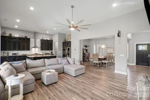 a living room with furniture kitchen view and a wooden floor