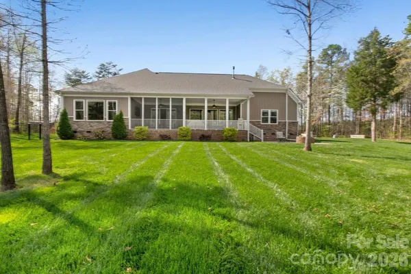 a view of a house next to a big yard and large trees