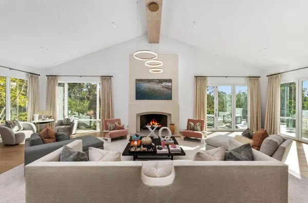 a living room with furniture fireplace and large windows