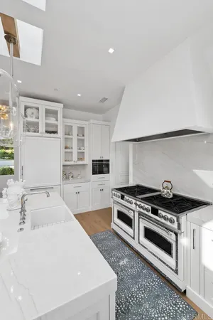 a kitchen with stainless steel appliances a stove a sink and white cabinets