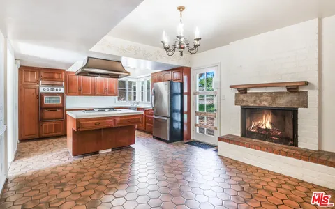 a open kitchen with kitchen island stainless steel appliances a stove refrigerator and a fireplace
